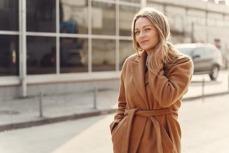 Eine Frau in einem braunen Mantel steht auf der Straße