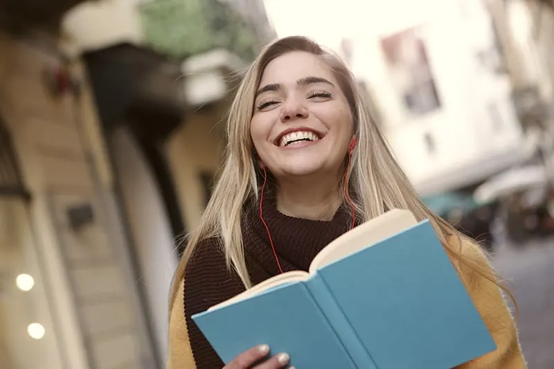 eine lächelnde Frau, die ein Buch liest