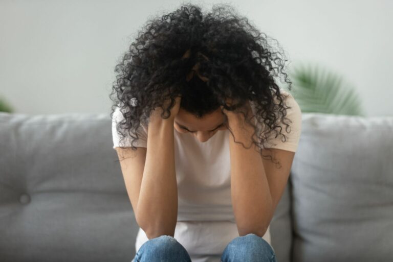 traurige Frau sitzt mit gesenktem Kopf