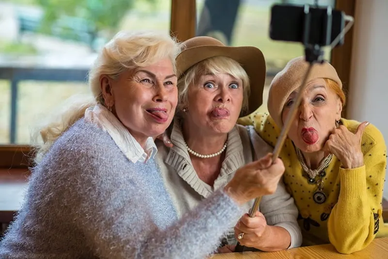 Ältere Frauen, die Zunge zeigen und wie Kinder herumalbern, während sie ein Selfie machen