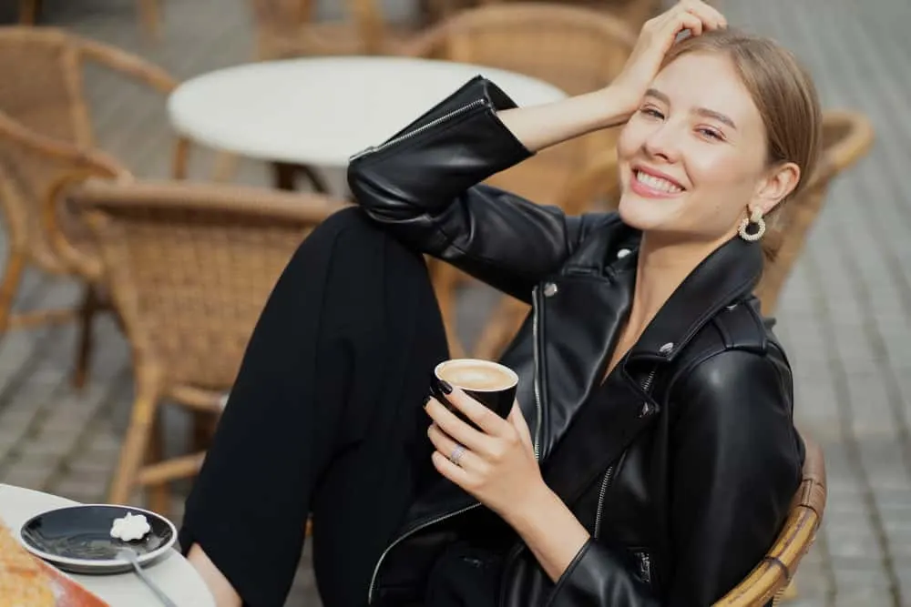 Auf der Terrasse des Cafés trinkt eine zufriedene glückliche Frau einen Cappuccino
