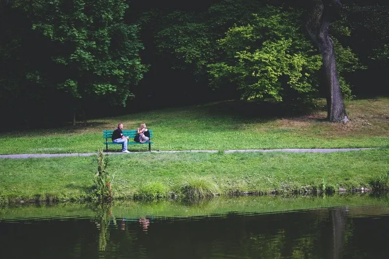 Auf einer grünen Bank am Fluss sitzt ein liebevolles Paar und redet