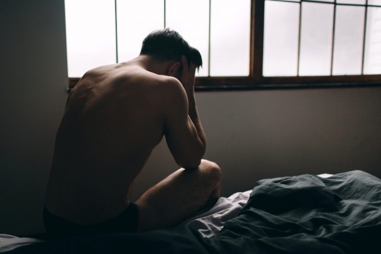 Ein trauriger Mann weint auf dem Bett