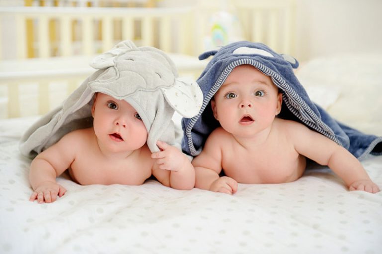 Zwillingsbabys liegen auf dem Bett