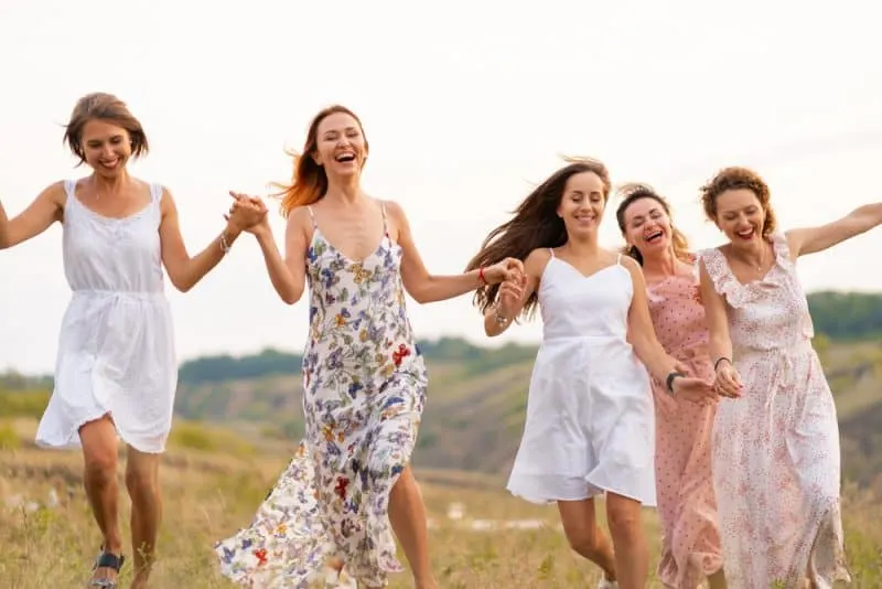 Fünf lächelnde Frauen rennen über das Feld