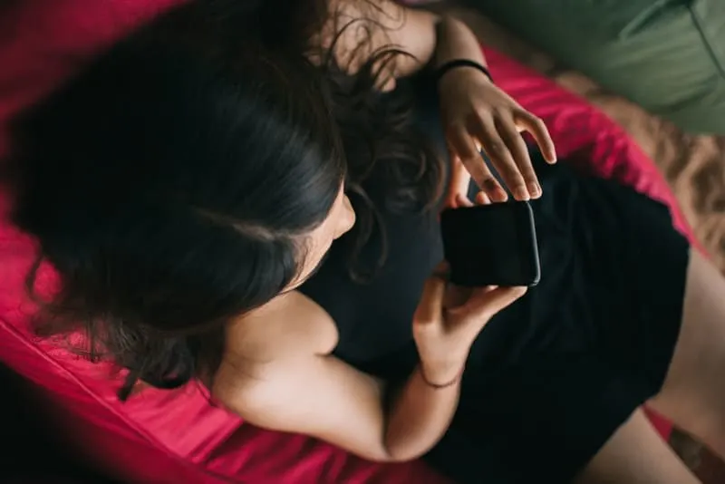 Ein Mädchen in einem schwarzen Kleid benutzt ein Handy