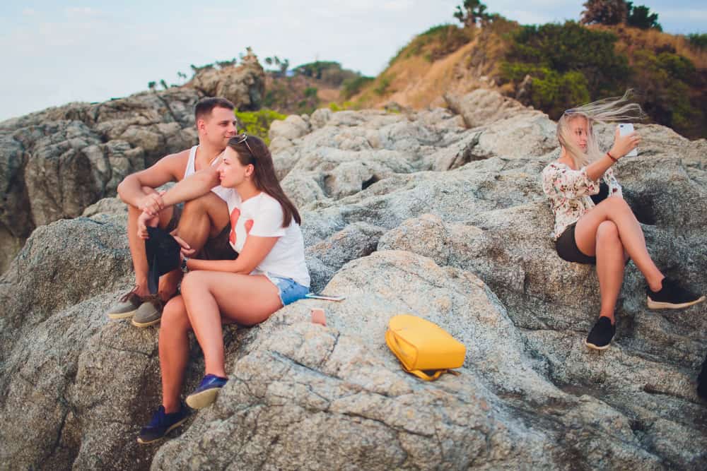 Ein Mann, der mit seiner Frau auf einem Felsen sitzt, beobachtet ein anderes Mädchen