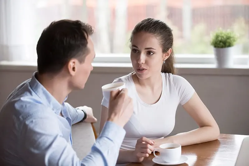 Ein Mann hört zu, wie seine Freundin mit ihm spricht, während er zusammen Kaffee trinkt