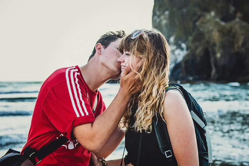 Ein Mann küsste seine Freundin auf die Wange, während er in der Nähe des Ozeans stand