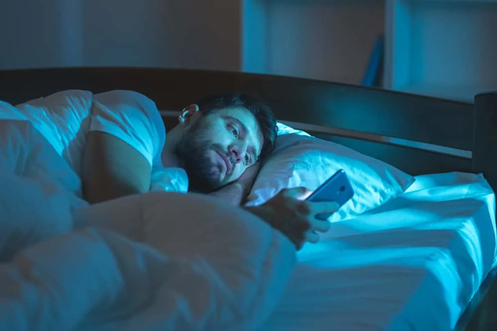Ein Mann liegt im Bett und benutzt ein Smartphone
