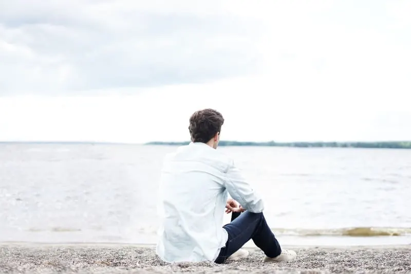 Ein Mann sitzt am Strand am Wasser(1)