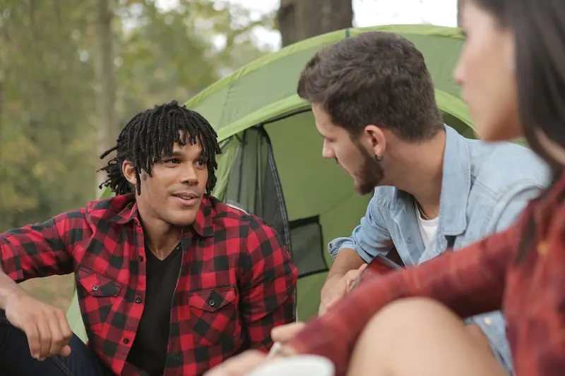 Ein Mann spricht mit seinen Freunden, während er vor dem Zelt sitzt