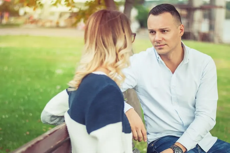 Ein Mann und eine Frau sitzen auf der Bank im Park bei einem Date
