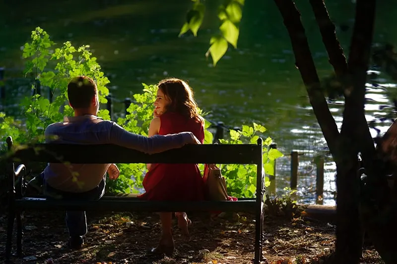 Ein Mann und eine Frau sitzen auf der Bank in der Nähe des Sees bei einem Date