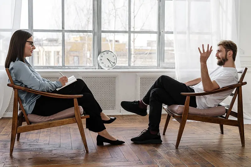 Ein Mann und eine Frau unterhalten sich, während sie sich im Sessel gegenüber sitzen