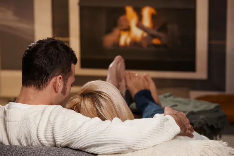 Ein Paar genießt es auf dem Sofa am Feuer, das im Kamin brennt
