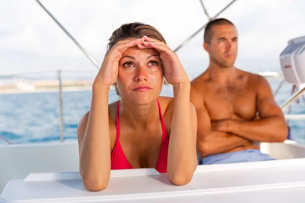 Ein trauriges Mädchen und ihr wütender Freund sitzen nach einem Streit auf einer Yacht