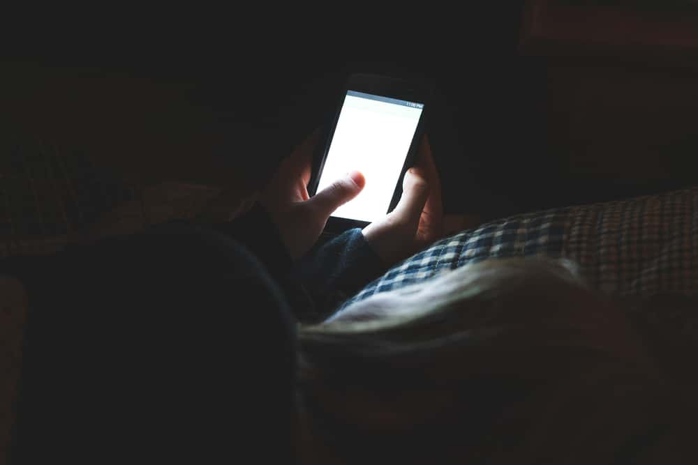 Eine Frau im Dunkeln schaut auf einen leeren Handybildschirm