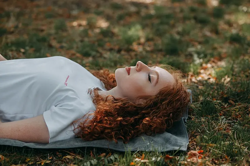 Eine Frau mit geschlossenen Augen lag auf der grauen Matte im Park