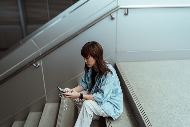 Eine Frau sitzt auf der Treppe und benutzt ein Handy