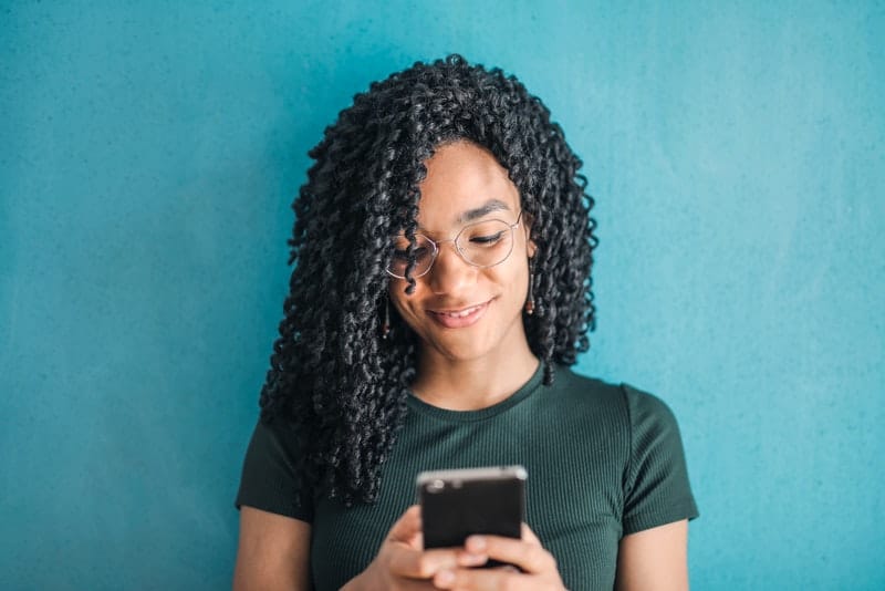 Eine lächelnde schwarze Frau schreibt eine SMS