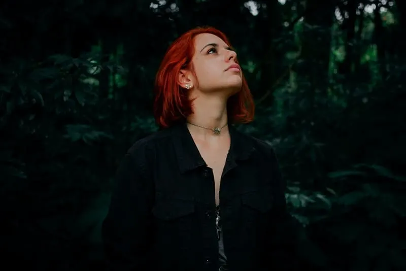 Eine rothaarige Frau steht im Wald
