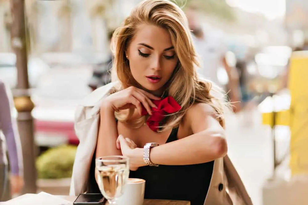 Eine schöne Blondine sitzt in einem Café und wartet ungeduldig auf jemanden