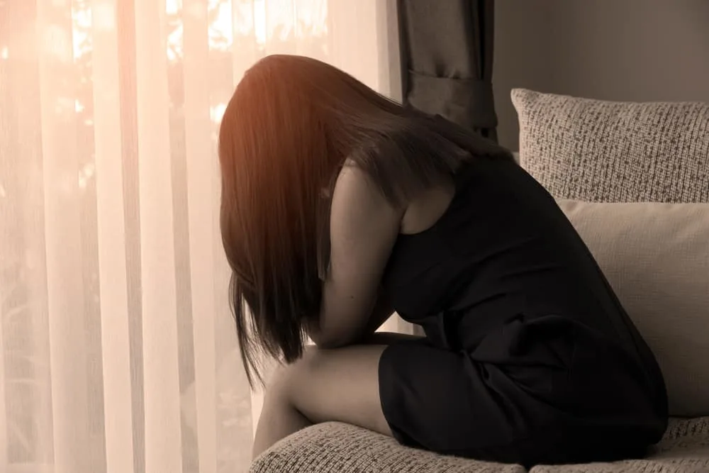 Eine traurige Frau sitzt auf dem Bett und weint