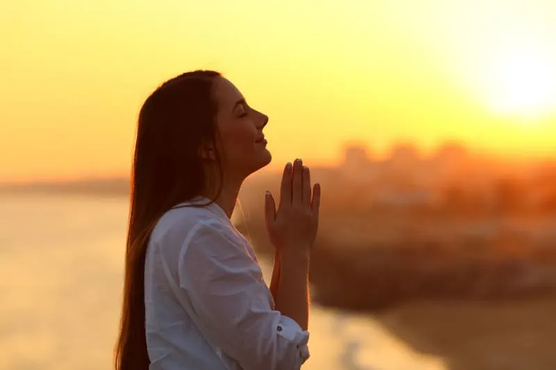 eine Frau, die bei Sonnenuntergang betet