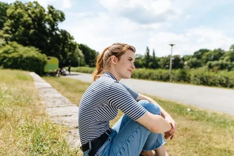 Frau in Jeans sitzt im Freien