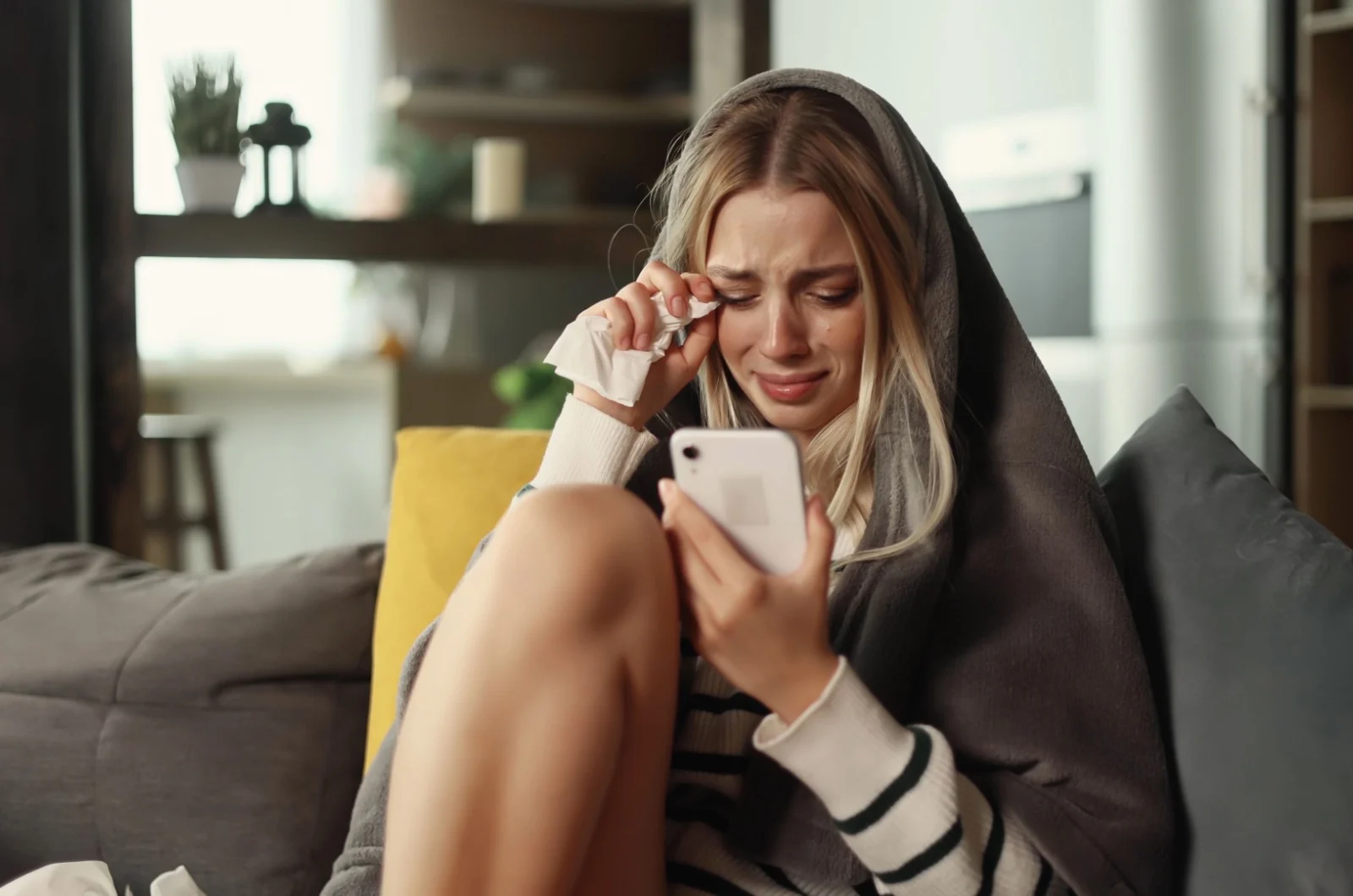 Frau haelt ein Telefon in der Hand und weint