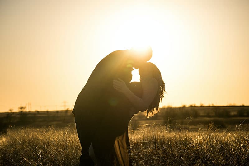Mann küsst eine Frau bei Sonnenuntergang