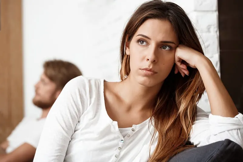 traurige Frau sitzt auf der Couch neben seinem Freund und ignoriert sie