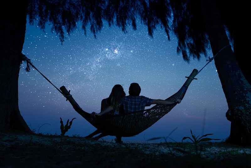 Paar, das sich in einer Hängematte entspannt und den Sternenhimmel genießt