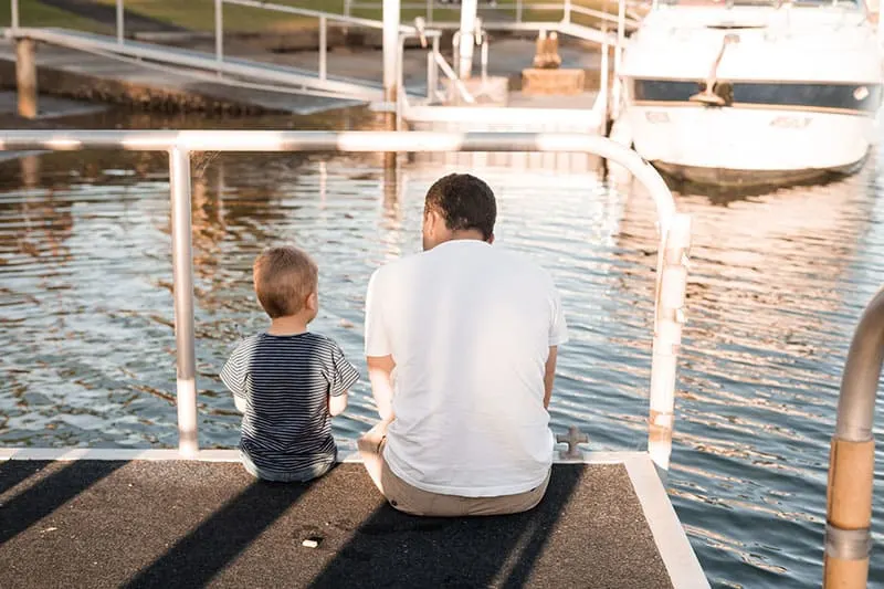 Vater sitzt mit seinem Sohn auf dem Pier