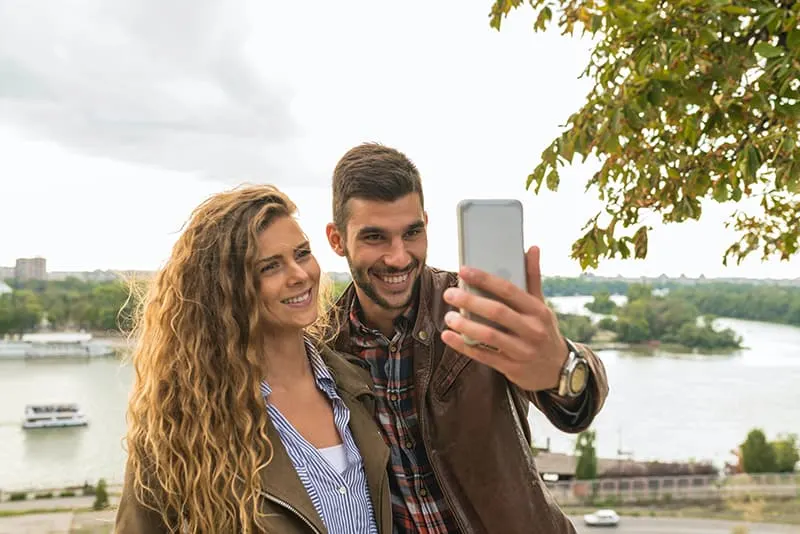 Ein lächelnder Mann und eine Frau machen ein Selfie mit einem Smartphone