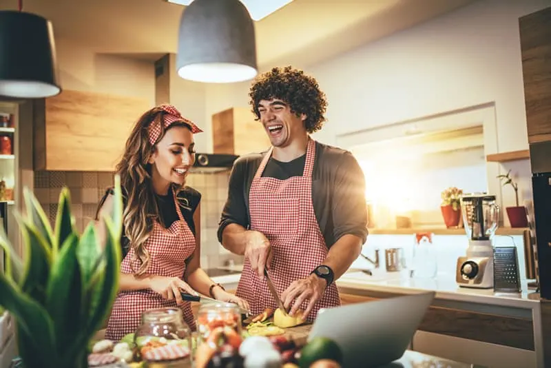Ein Mann und eine Frau bereiten Essen in der Küche zu und lachen