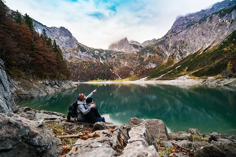 Ein Paar sitzt auf dem Felsen in der Nähe des Sees und beobachtet die Natur
