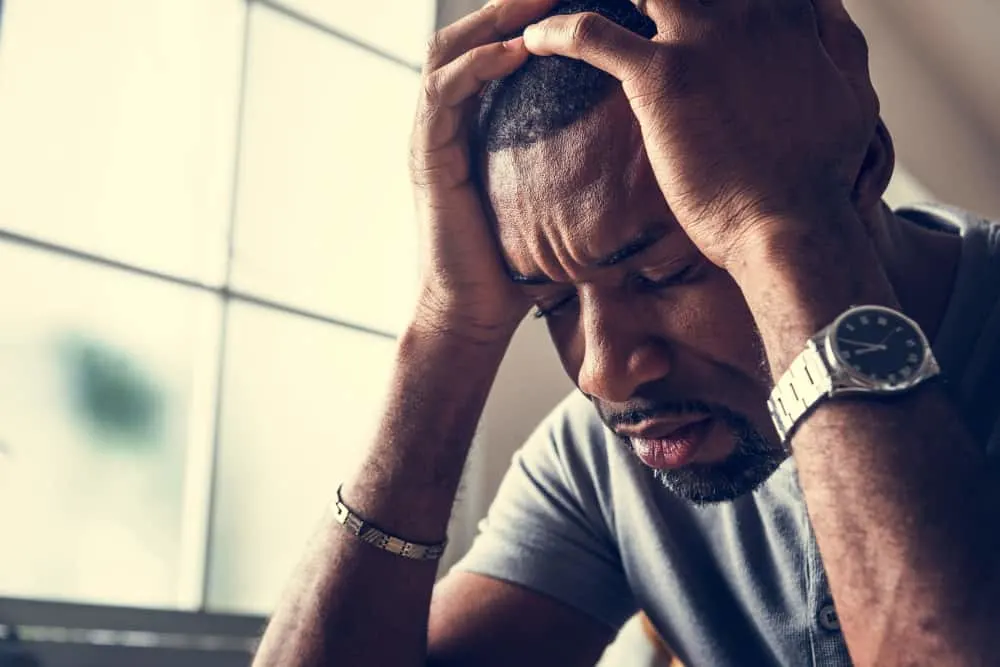 ein Porträt eines depressiven schwarzen Mannes, der seinen Kopf hält