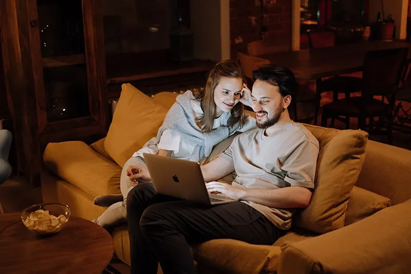 ein lächelndes Paar sitzt abends auf der Couch