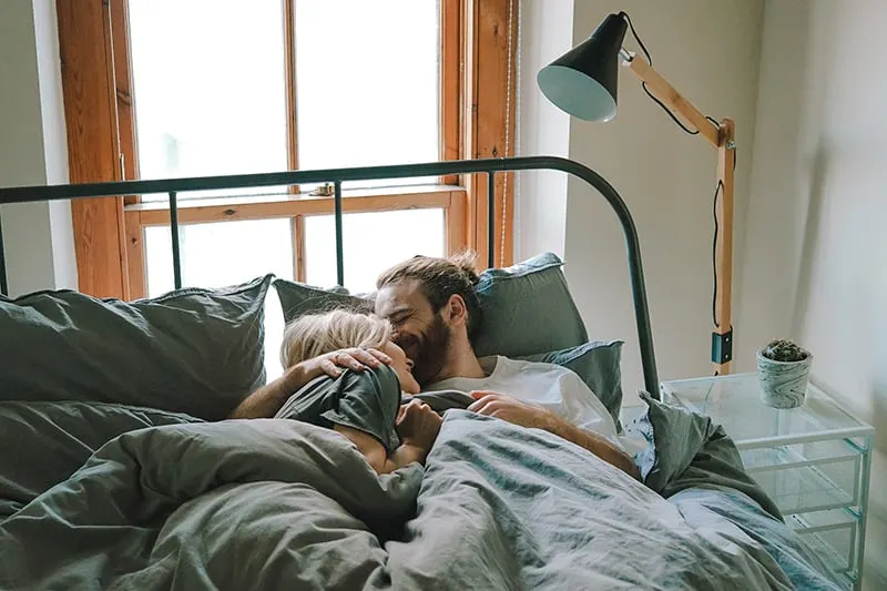 Ein liebevolles Paar, das sich morgens im Bett umarmt