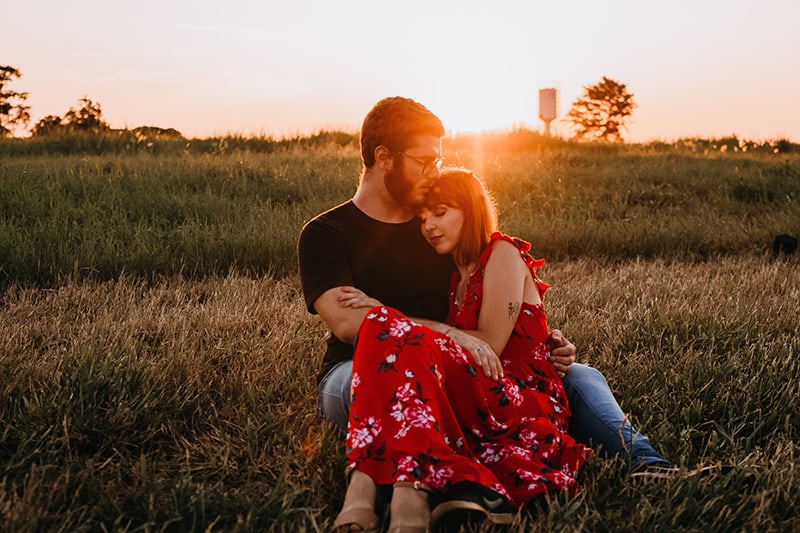 ein liebendes Paar, das während des Sonnenuntergangs auf dem Gras sitzt