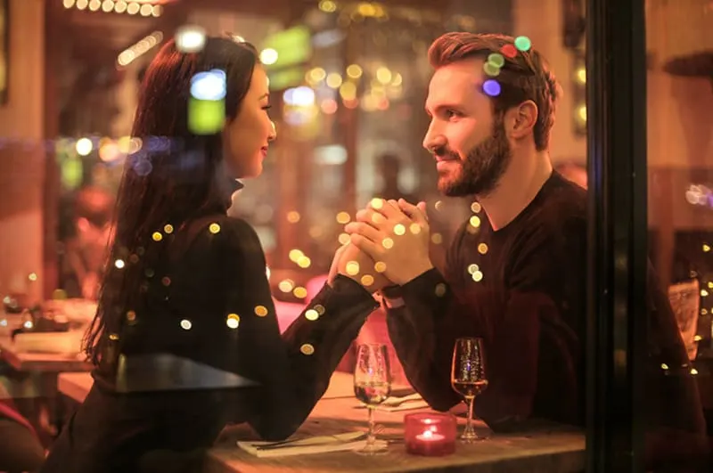 ein liebevolles Paar Händchen haltend im romantischen Restaurant bei einem Date