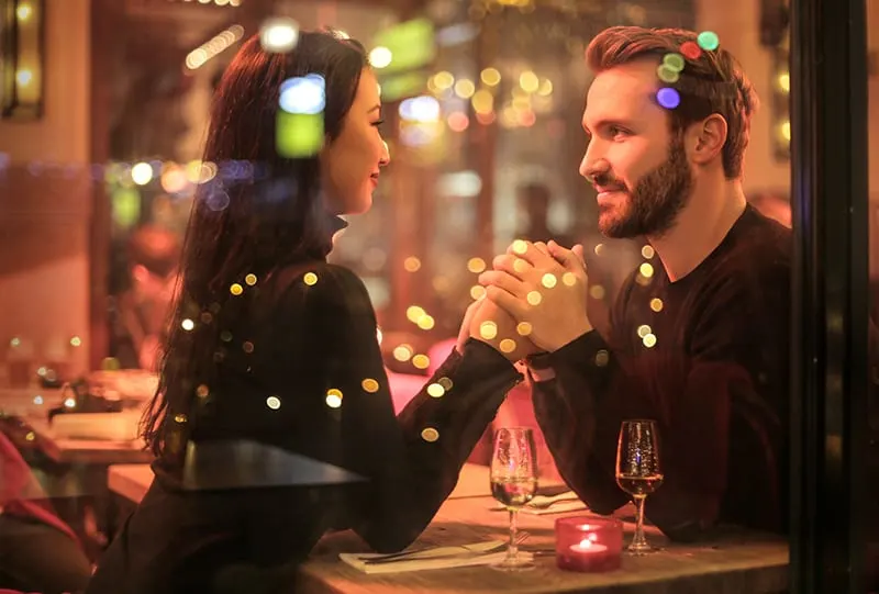 Ein Paar, das sich an den Händen hält und sich im romantischen Restaurant ansieht