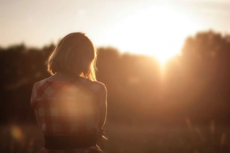 eine Frau, die einen Sonnenaufgang beobachtet, während sie alleine steht