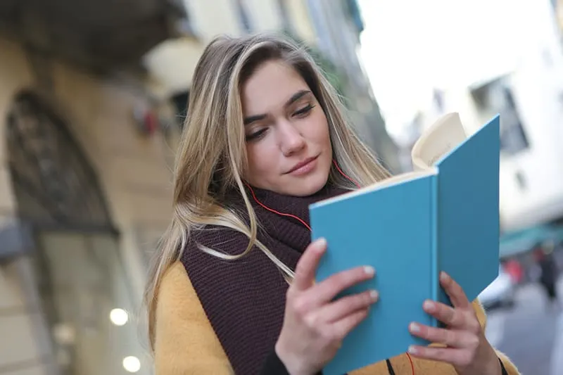 eine Frau, die ein Buch liest, während sie auf der Straße steht