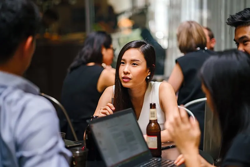 eine Frau, die einem Mann zuhört, während sie mit Freunden im Café sitzt