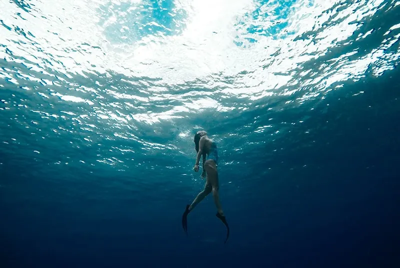 eine Frau, die unter Wasser mit Schwimmflossen schwimmt