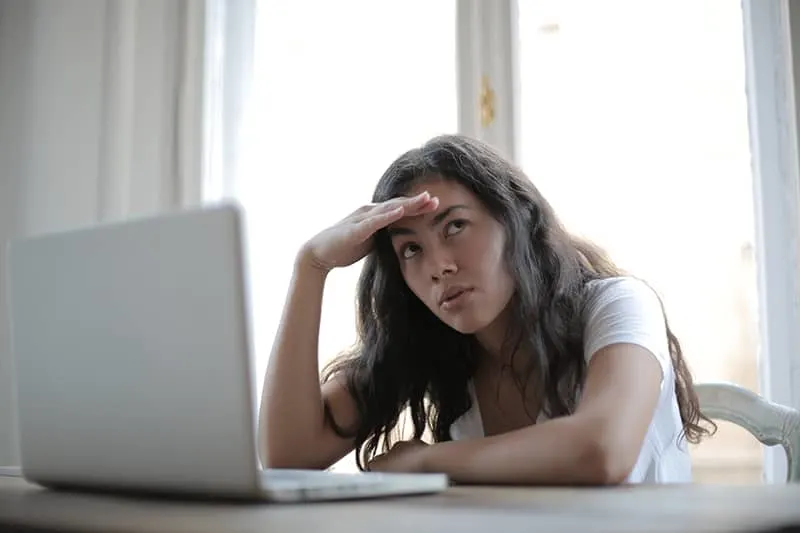 Eine Frau schaut zur Seite und verliert die Geduld, während sie vor dem Laptop sitzt