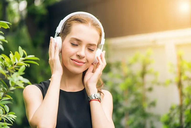 eine Frau mit Kopfhörern, die Musik hört, während sie draußen steht